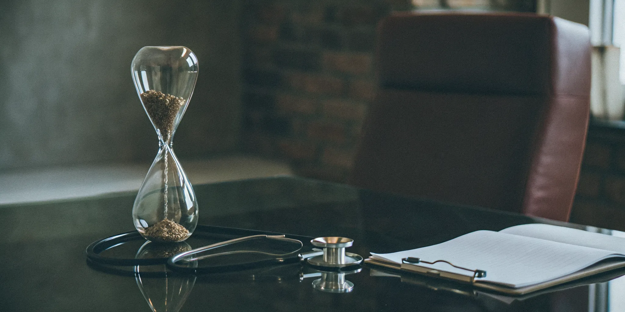 Hourglass, stethoscope, and paperwork showing the financial impact of Medicaid reimbursement delays.